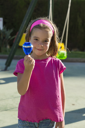 Little girl playing with a spinning top in a playgroundの写真素材
