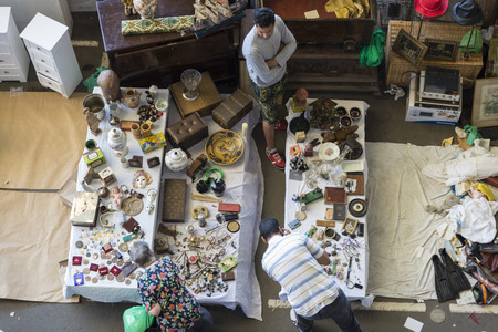 Barcelona, Spain - June 18, 2014   Seller at his post of objects and furniture resale while two clients are looking for something to buy in the most famous flea market in Barcelona, also known as Els Encants or Els Encants Vells, located in Glories neighbのeditorial素材