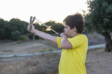 Ten-year-old is ready to fire his slingshot in a forestの写真素材