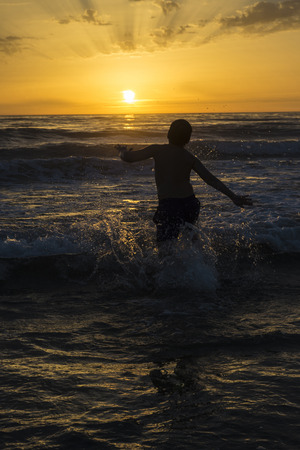 boy bathing on the beach at dusk on a beach in Andalusia, Spainの写真素材