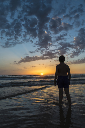boy bathing on the beach at dusk on a beach in Andalusia, Spainの写真素材
