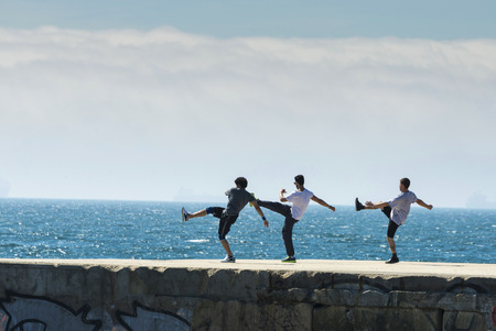 Barcelona, Spain - April 7, 2014: three young men doing exercise in a Barcelona breakwater looking at the horizonのeditorial素材