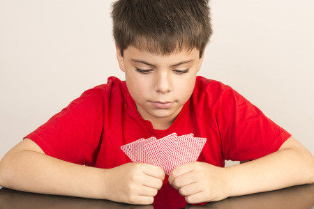 Thoughtful young boy playing cardsの写真素材