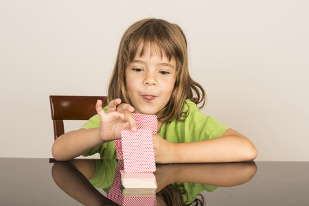 portrait of little girl playing cards while pulling the tongueの写真素材