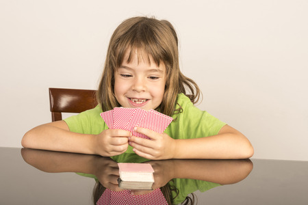 portrait of smiling little girl playing cardsの写真素材