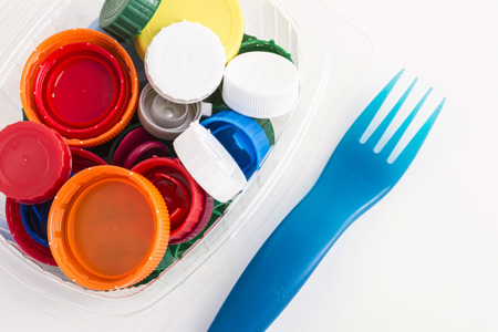 lots of plastic plugs in a plastic container with a fork isolated on white backgroundの写真素材