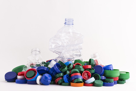 lots of plastic plugs with three crushed plastic bottles isolated on white background