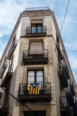 Facade of an ancient building in the old town of Barcelona known as Barri Gotic with the independence flag hanging on a balconyのeditorial素材