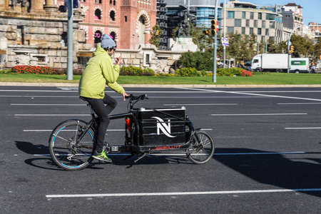 Barcelona, Spain - November 7, 2014: An interesting bike with a cargo box running through a square in Barcelonaのeditorial素材