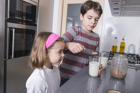Children getting ready a glass of chocolate milkの写真素材