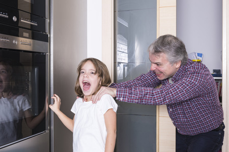 Father surprises his daughter taking candyの写真素材