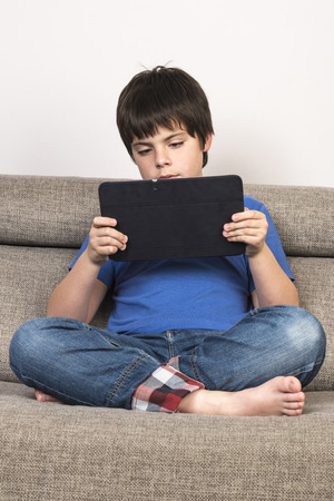 Young boy using tablet digital on the sofa.の写真素材