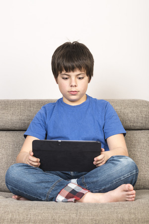 Young boy using tablet digital on the sofa.の写真素材