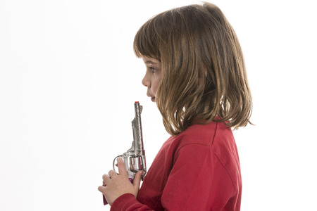 Little girl blowing a toy gun