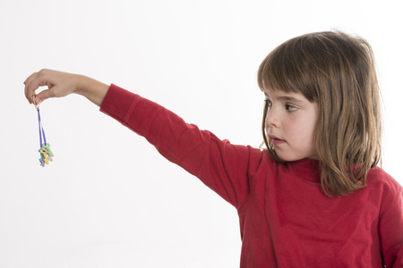 Little girl looking at a small colored keys  isolated on white backgroundの写真素材