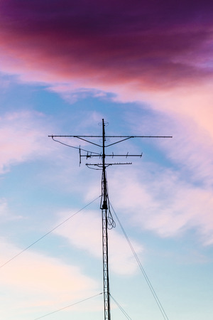 Silhouette of antenna backlit at sunset with colorful sky cloudsの写真素材