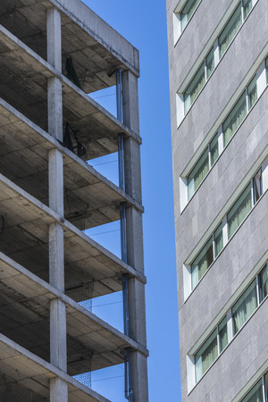 Skyscraper under construction with safety rails against another building constructedの写真素材