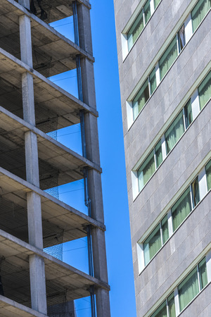 Skyscraper under construction with safety rails against another building constructedの写真素材