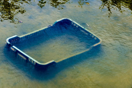 Plastic boxes pulled into a river with contaminated waterの写真素材