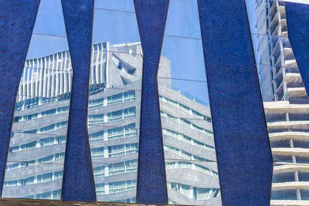 Skyscrapers, one under construction, reflected in the mirrors of a lilac wallの写真素材