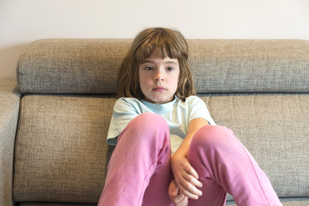 Little girl watching TV sitting on the couchの写真素材