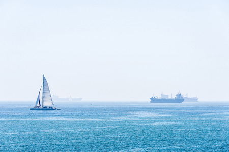 Barcelona, Spain - May 2, 2015: Sailboat , catamaran and surfer sailing between cargo ships in Barcelona, Catalonia, Spainのeditorial素材