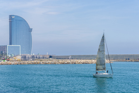 Barcelona, Spain - May 2, 2015: Sailboat sailing out of the harbor with the W hotel in the backgroundのeditorial素材