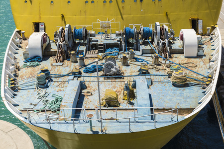 Deck of a ship with coils of chains and ropes tied in a harborの写真素材