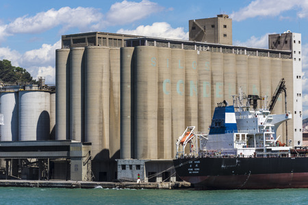 Barcelona, Spain - May 23, 2014: Cargo ship docked waiting beside silos in the port of Barcelonaのeditorial素材