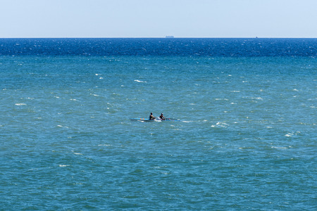 Two men rowing in a pirogue at sea