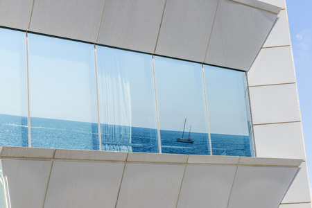 Sailboat reflected on a window of a modern building in Barcelona, Catalonia, Spainの写真素材