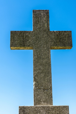 Stone cross against blue sky in a cemetery.の写真素材