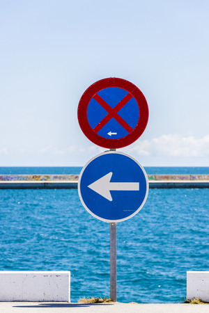 No parking sign and another sign of compulsory direction with the sea and sky backgroundの写真素材