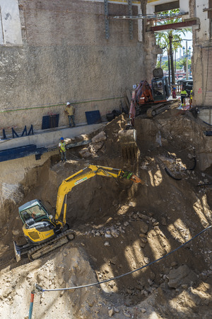 Barcelona, Spain - June 4, 2015: Construction of a building keeping the old facade through a system of beams. The workers and their bulldozers are doing the foundations of the new buildingのeditorial素材
