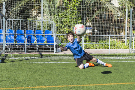 Young football goalkeeper stretching to stop a ballの写真素材