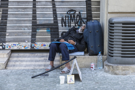 Barcelona, Spain - May 26, 2015: Tramp sleeping at the gates of a closed tradeのeditorial素材