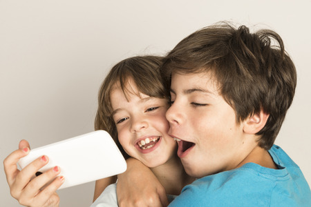 Happy child take a selfie with a smartphone at home isolated on white backgroundの写真素材