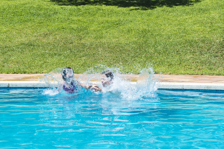 Children jumping in pump together in an outdoor poolの写真素材