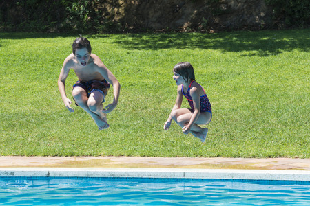 Children jumping in pump together in an outdoor poolの写真素材