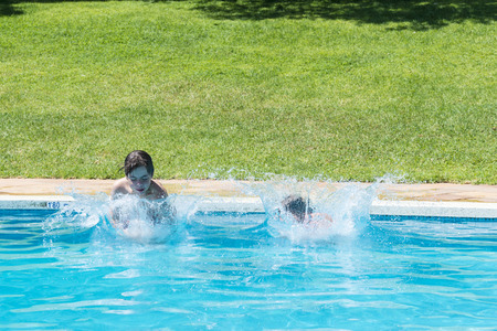 Children jumping in pump together in an outdoor poolの写真素材