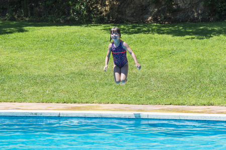 Little girl jumping in pump in an outdoor poolの写真素材