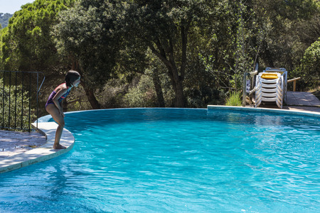 Little girl about to jump in an outdoor pool in Costa Brava, Catalonia, Spainの写真素材
