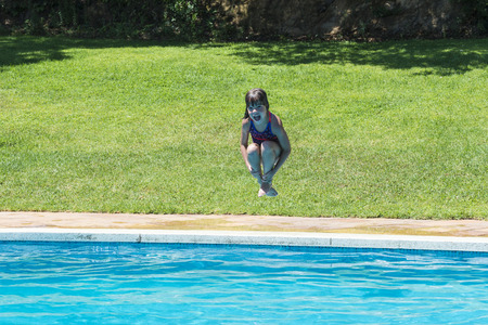 Little girl jumping in pump in an outdoor poolの写真素材