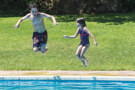 Children jumping in pump together in an outdoor poolの写真素材