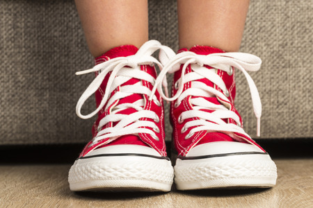 Little girl wearing a pair of red sneakers at homeの写真素材