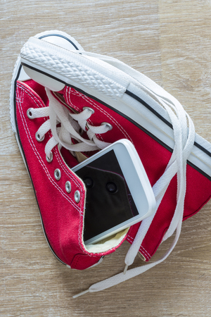Pair of red sneakers and a smart phone seen from above on a parquet floorの写真素材