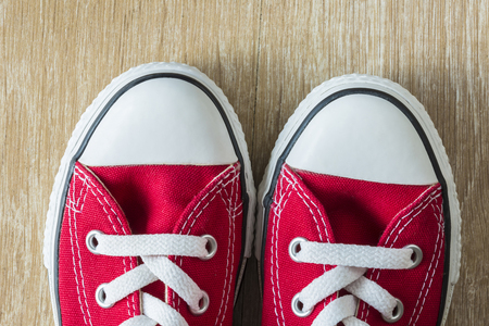 Closeup of a pair of red sneakers seen from above on a parquet floorの写真素材