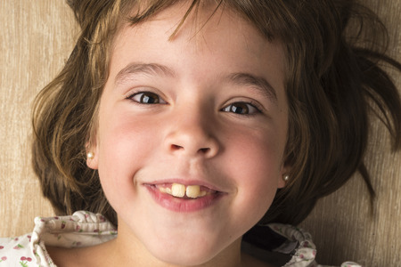 Portrait of little girl smiling stretched on the floor looking at cameraの写真素材