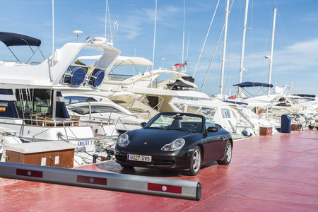 Puerto Banus, Spain - August 15, 2015: Porsche parked next to luxury yachts moored in Puerto Banus, a marina near Marbella, Andalusia, Spain. A barrier prevents the passage of vesselsのeditorial素材