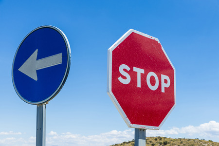 Stop sign and signal direction compulsory against the sky in Spainの写真素材